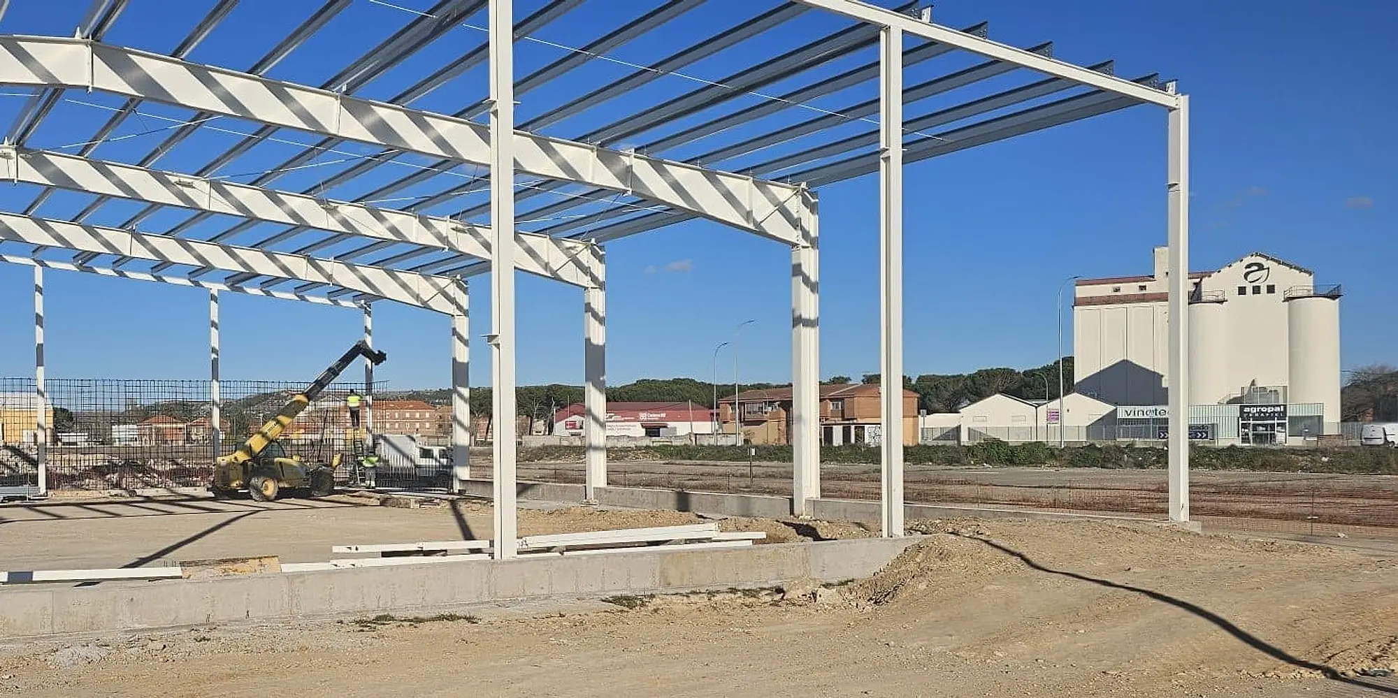 Pórticos metálicos de la nave en obra, con una plataforma elevadora y un silo al fondo