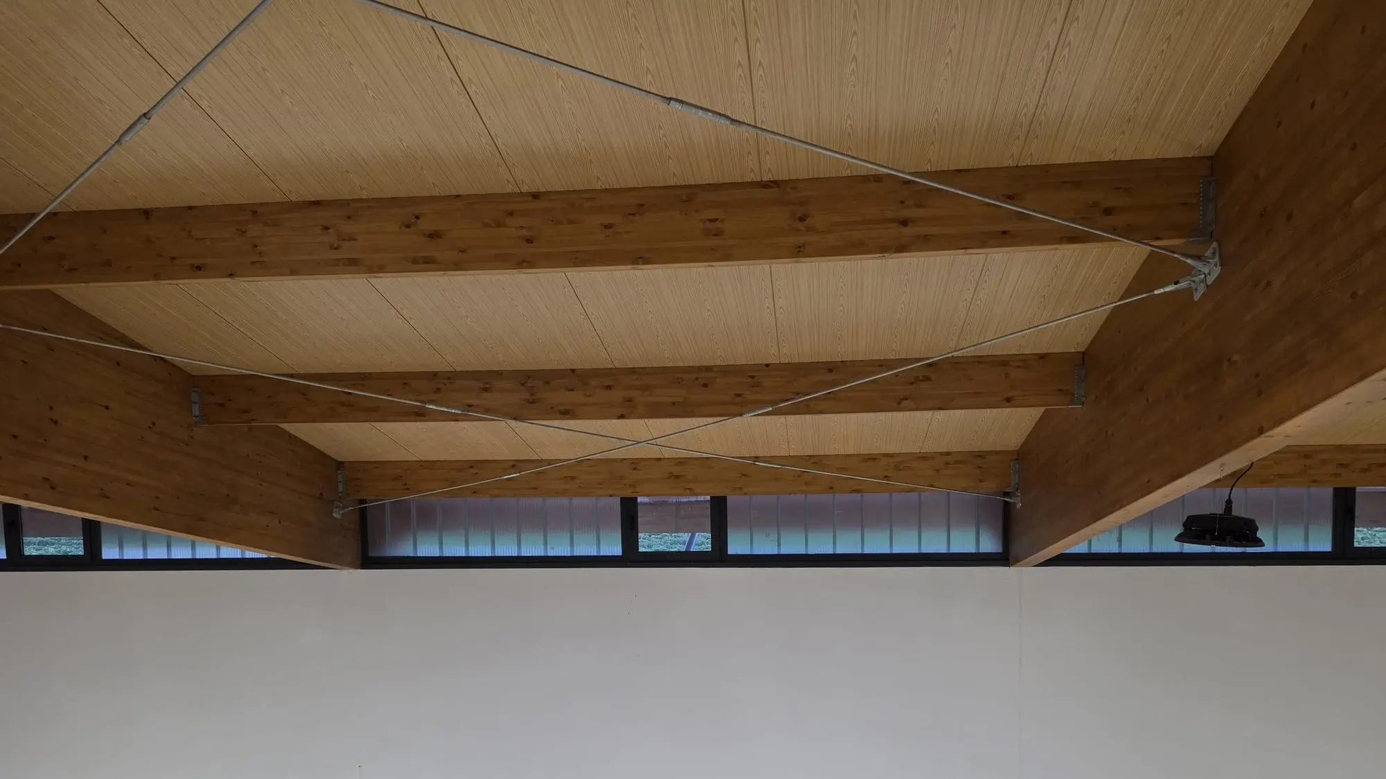 Vigas de madera laminada y ventanas corridas en lo alto de la sala de depósitos