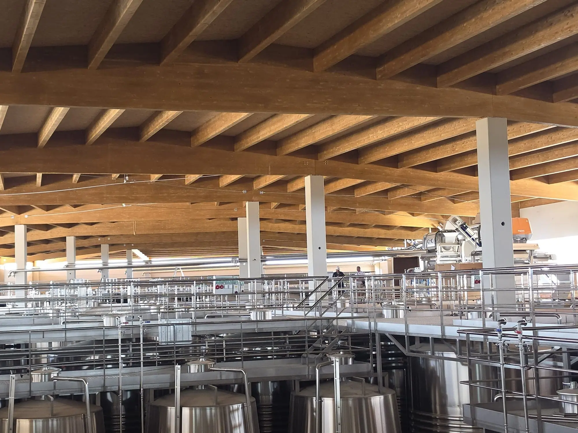 Pilares blancos y vigas de madera laminada sobre los depósitos y pasarelas de acero