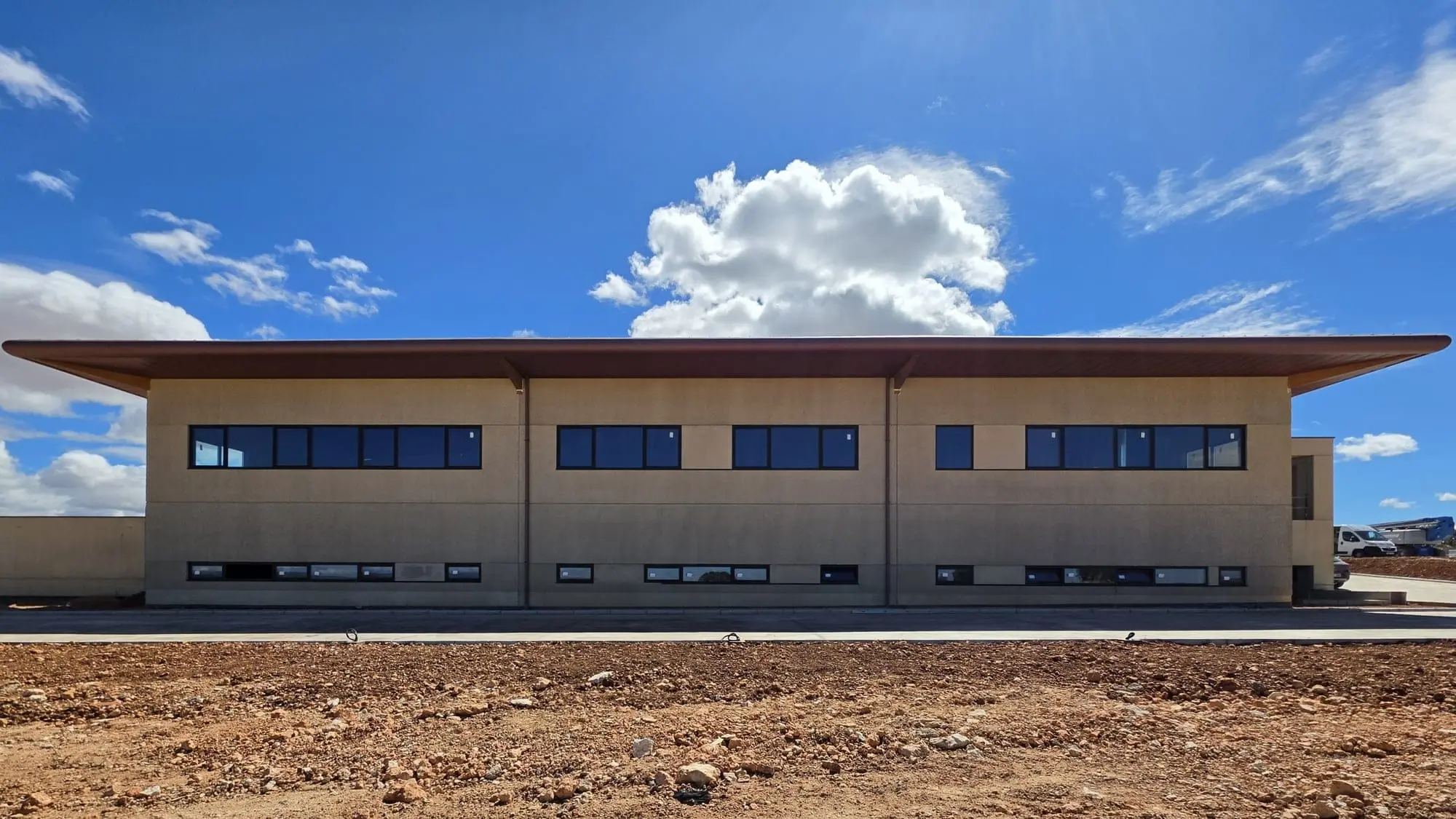 Fachada de la bodega con ventanas corridas y un gran alero, bajo un cielo azul