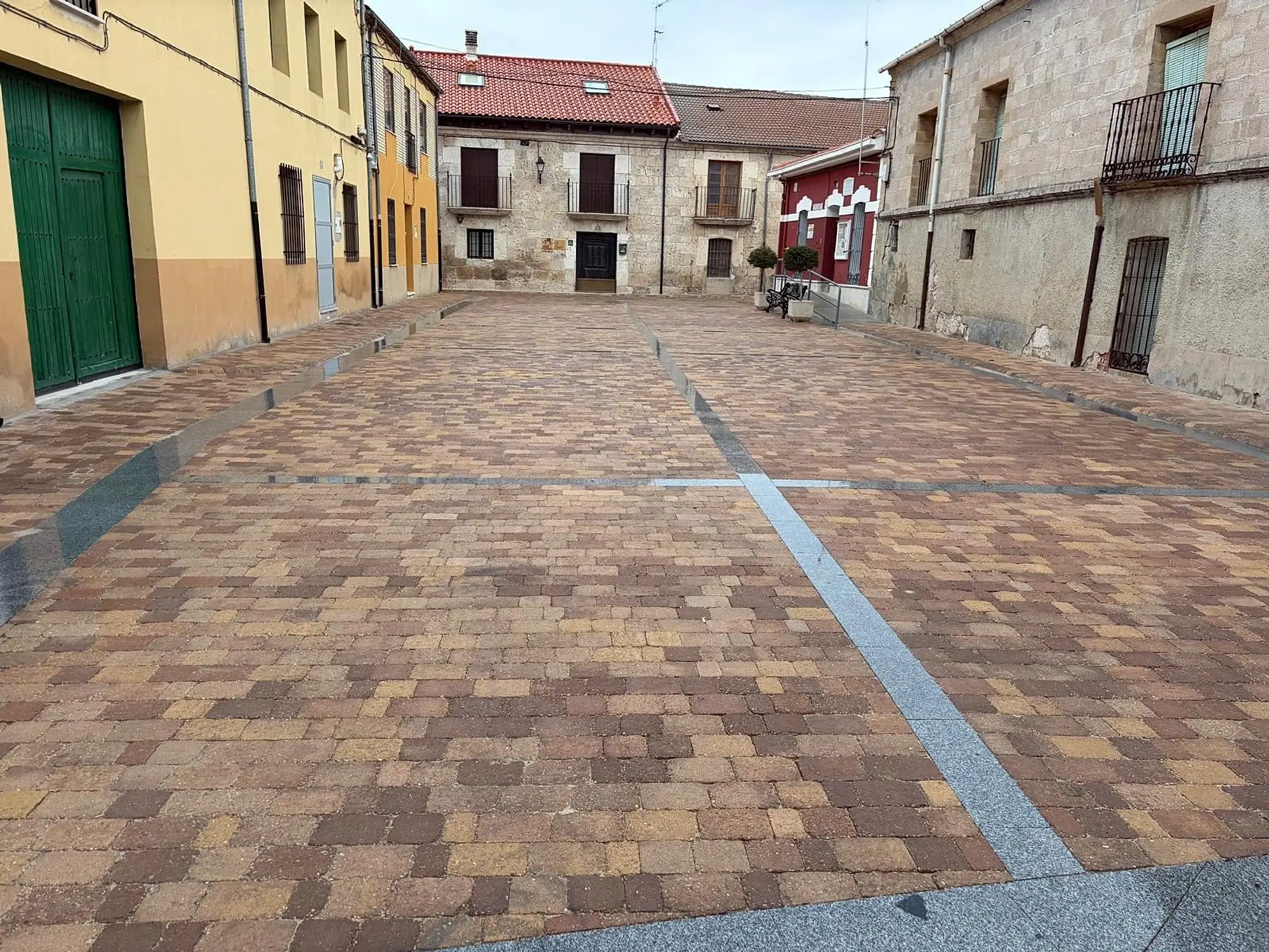 Cruce de calles adoquinado con bandas de piedra gris, entre casas de piedra y fachadas de colores